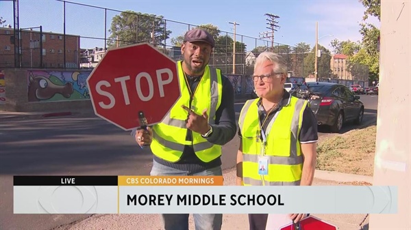 CBS Colorado's Justin Adams helps students cross the street as a celebrity crossing guard